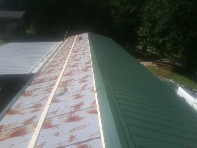 Old rusted panels beside newly installed green metal roofing — Wind Damage Roof Repair by Roofing Brothers in La Fayette