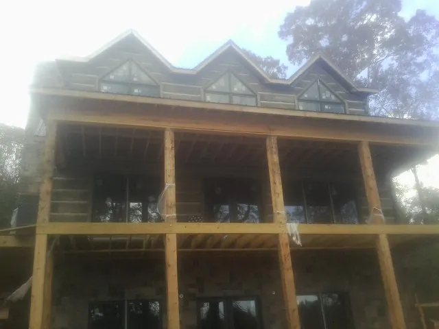 Dormers and porch framing on a large log home under construction — Roof Coating work by our crew in La Fayette