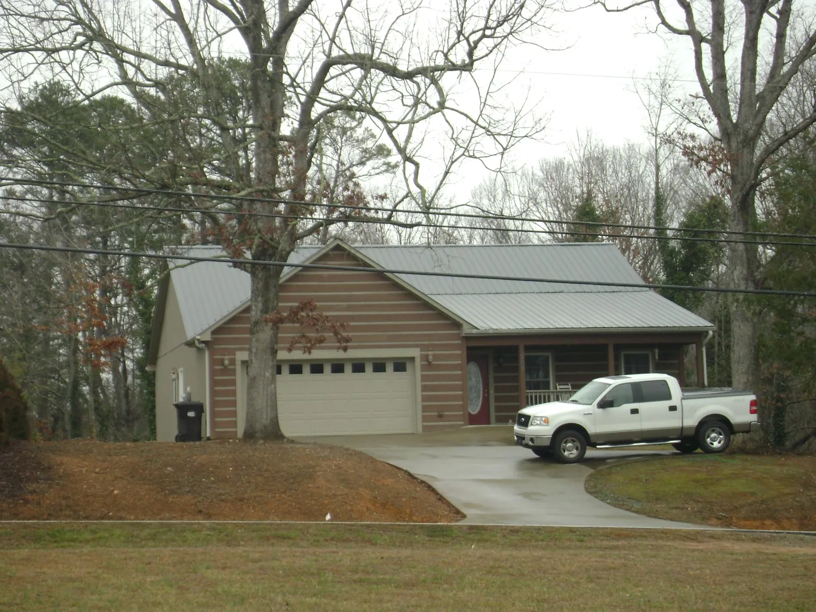 Gray metal roof on a log sided house with an attached two car garage in La Fayette