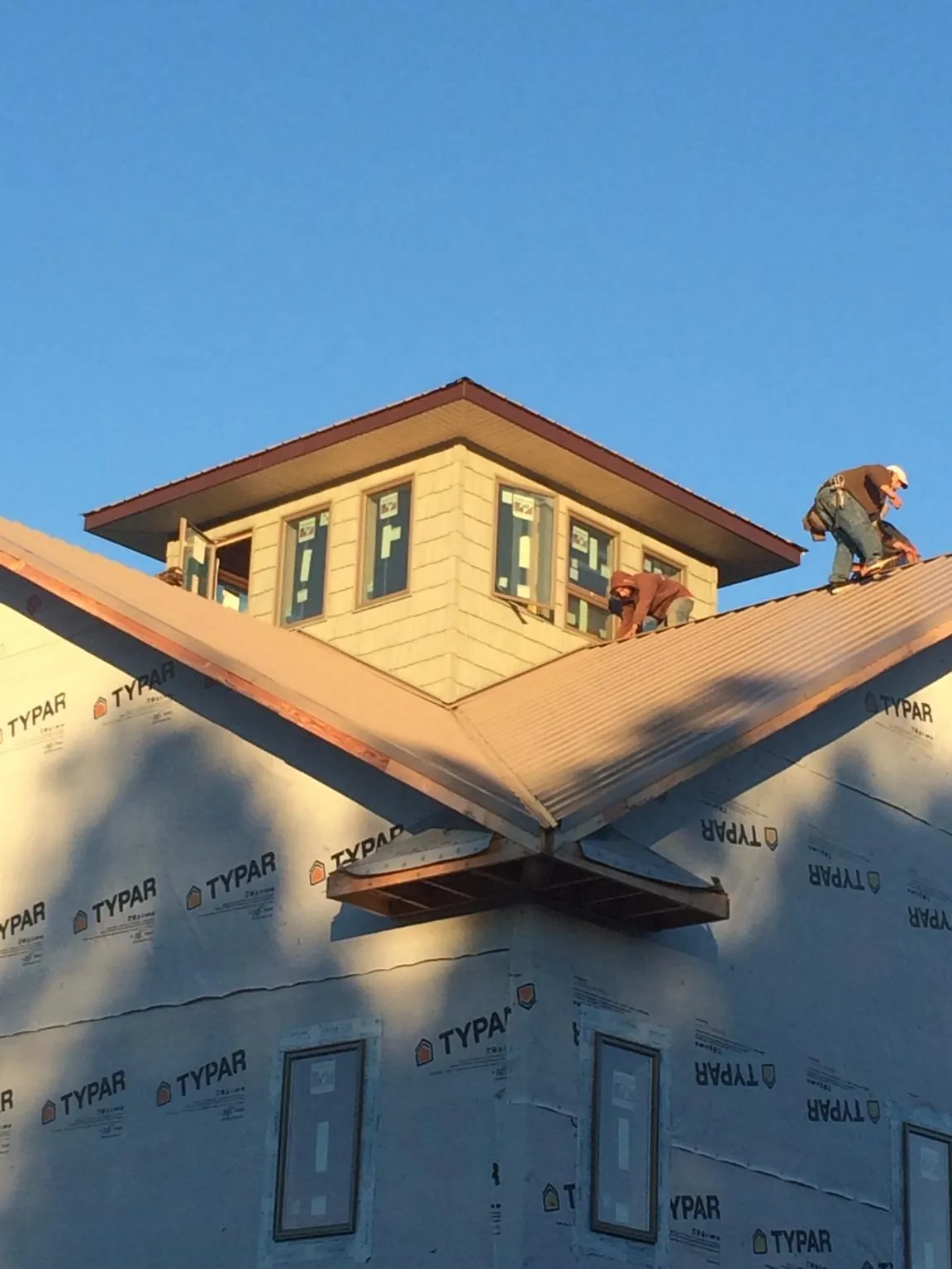 Roofers working around a rooftop cupola on a new metal roof at sunset — Roof Waterproofing in La Fayette by Roofing Brothers